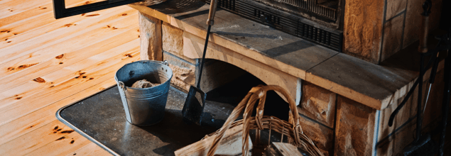 Ein Eimer und Reinigungszubehör stehen vor einem geöffneten Kamin.