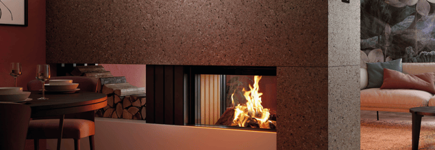 Ein Kaminofen mit Holzfach steht zwischen einem edel eingerichteten Ess- und Wohnbereich und dient als Raumteiler.