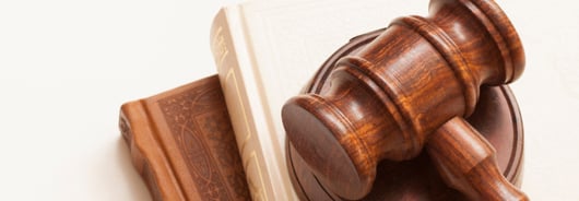 Ein hölzerner Richterhammer liegt auf zwei Büchern.