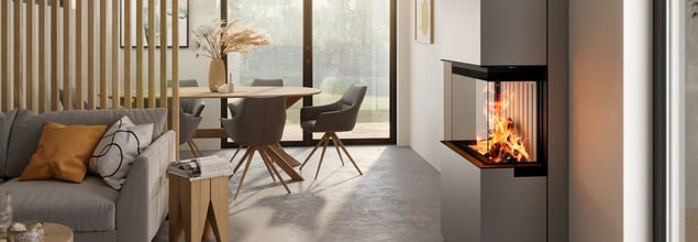 Ein grauer Kaminofen mit brennendem Feuer steht in einem modernen Wohnzimmer.