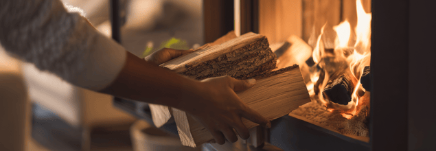 Person, die Feuerholz nachlegt.